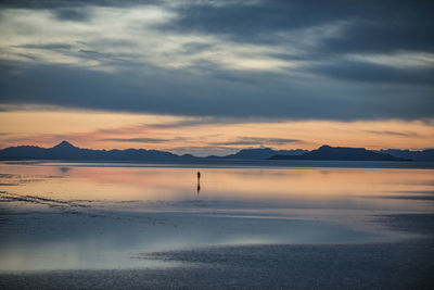 Silhouette person standing on bonneville salt flats against cloudy sky