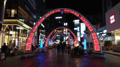 People walking on illuminated street at night