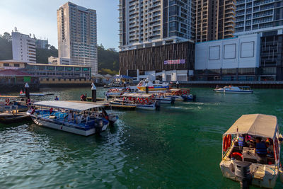 Boats moored in river by buildings in city