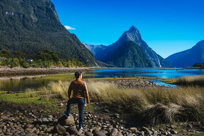 Rear view of man standing on stone against mountains