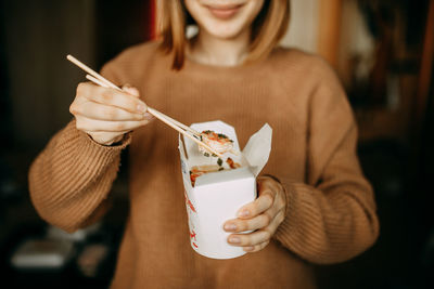 Midsection of woman eating food at home