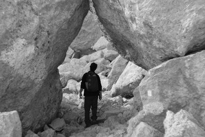 Rear view of man standing amidst rocks