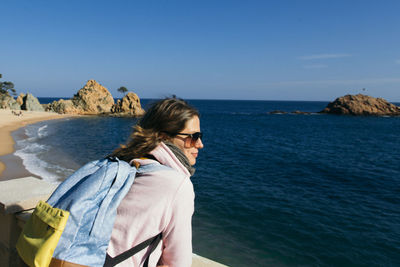 Close-up of woman on beach against clear blue sky