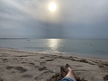 Low section of person on beach against sky