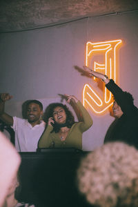Happy young female dj amidst friends enjoying at nightclub