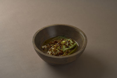 Romaine lettuce, miso broth and sourdough in a wooden bowl with brown background