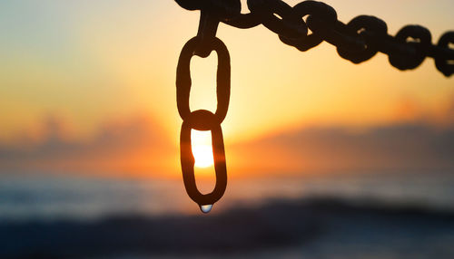 Close-up of silhouette chain against sky during sunset