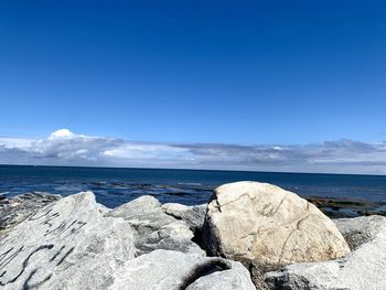 Rocks on beach against blue sky