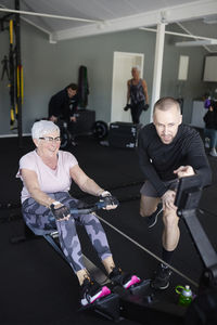 Coach assisting to senior woman exercising in gym