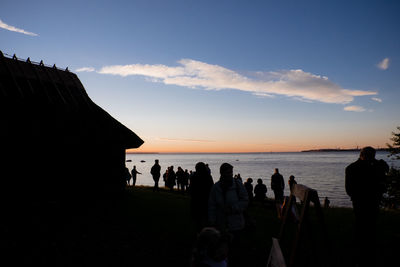 Silhouette people on beach against sky during sunset