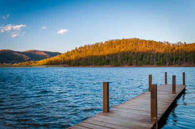 Wooden pier over lake against sky