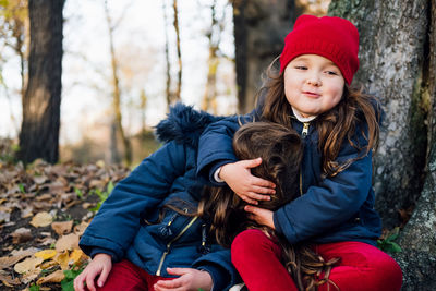 Smiling girl playing with sister in forest