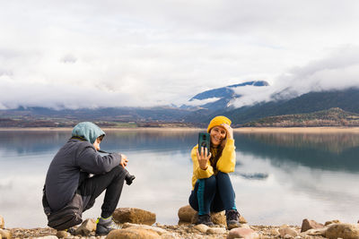 Rear view of woman sitting on rock against mountain