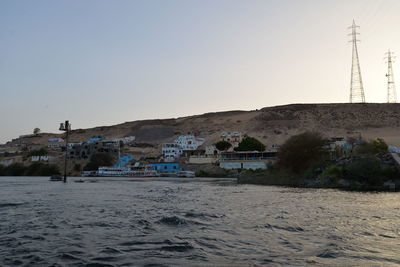 Buildings by sea against clear sky