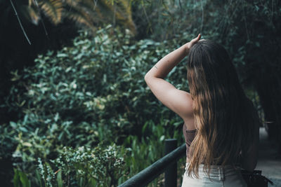 Rear view of woman standing against trees