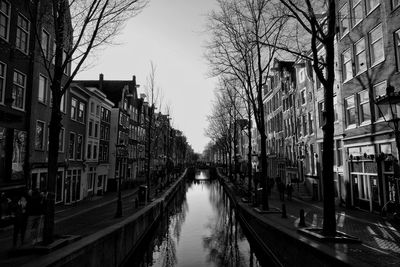 Canal amidst city buildings against sky