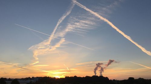 Low angle view of vapor trails in sky during sunset