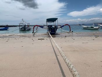 Boat moored on beach against sky