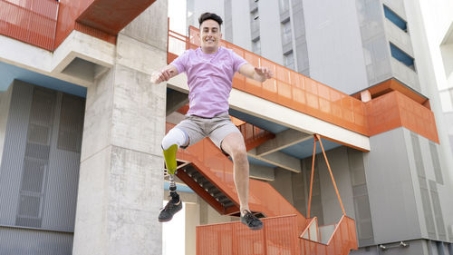 Carefree young man with amputation jumping against building