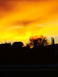 Silhouette trees against orange sky