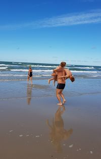 Full length of friends on beach against sky