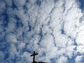 Low angle view of weather vane against cloudy sky