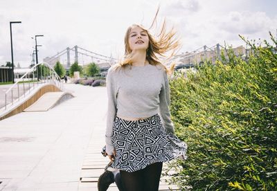 Portrait of a young woman with windy blonde hair on road