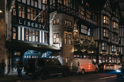 Cars on road by buildings in city at night