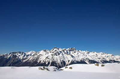 Snowcapped mountains against clear blue sky