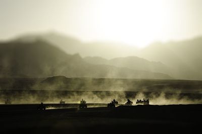 High angle view of silhouette people riding quadbike on field