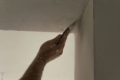 Cropped hand of man plastering ceiling