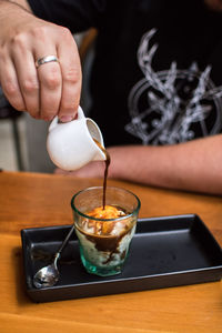 Close-up of hand pouring tea in cup on table