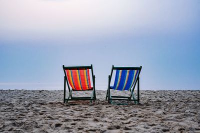 Chairs on beach against sky