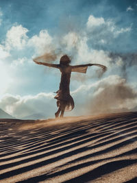 Low angle view of woman with arms outstretched against sky