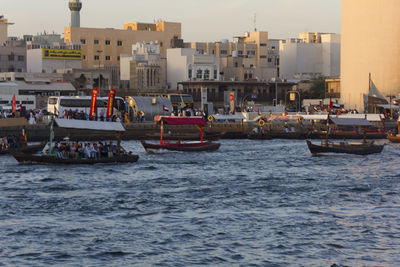 Boats sailing on sea against buildings in city