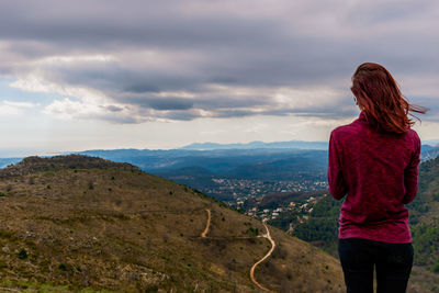 Rear view of woman standing on landscape against sky