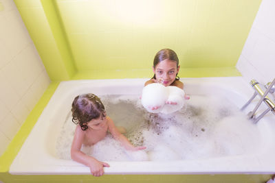 High angle view of siblings playing in bathtub