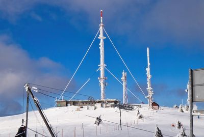 Low angle view of snowcapped mountain with radio relay against sky