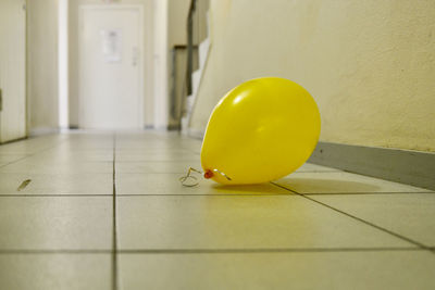 Close-up of yellow balloons on floor against wall at home
