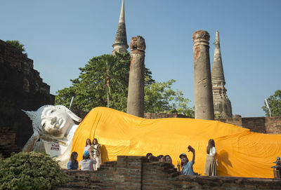 Tourist visiting buddhist temple against blue sky