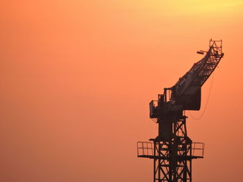 Low angle view of silhouette cranes against sky during sunset