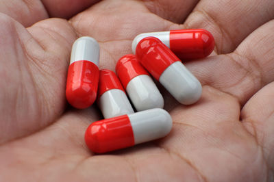 Close-up of hand holding red capsules