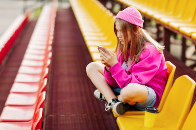 A teenage girl sits on the school bleachers and writes a message on her phone in her free time