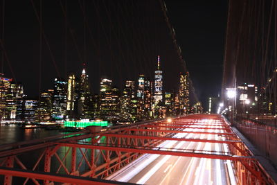 Illuminated bridge and buildings against sky at night