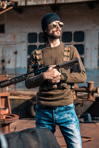 Man holding camera while standing against built structure