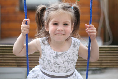 Portrait of smiling innocent girl on swing