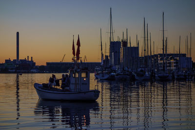 Boats moored at harbor against sky during sunset