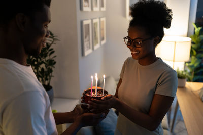 Happy young african woman smiling while loving husband giving her homemade pie for valentine's day