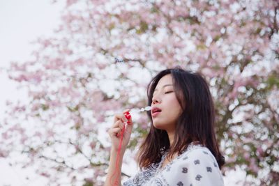 Beautiful woman with pink flower against white background