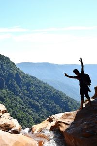 Rear view of man standing on mountain against sky